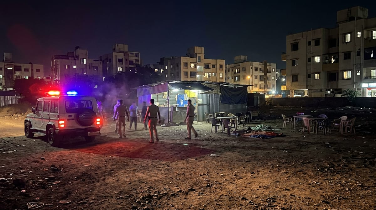 playing cards and cash scattered on a mat on an open ground at night, lit by a police torch beam