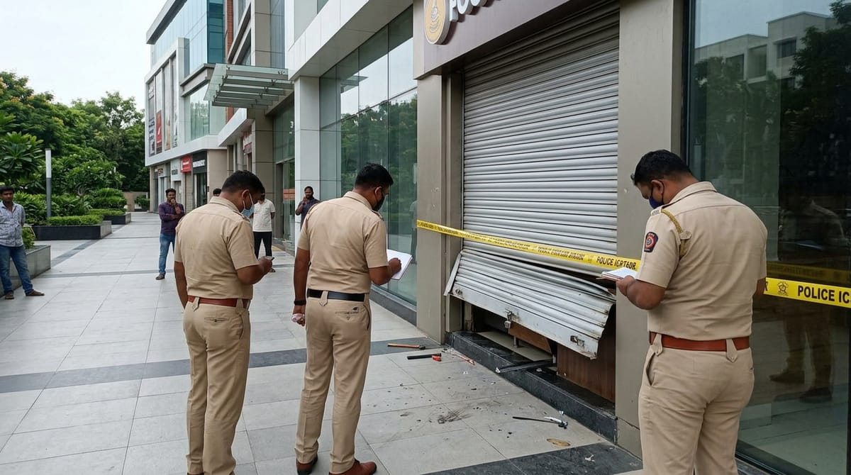 दो पुलिस अधिकारी एक दुकान का निरीक्षण कर रहे हैं, जबकि कुछ लोग दूर फर्श पोंछ रहे हैं।